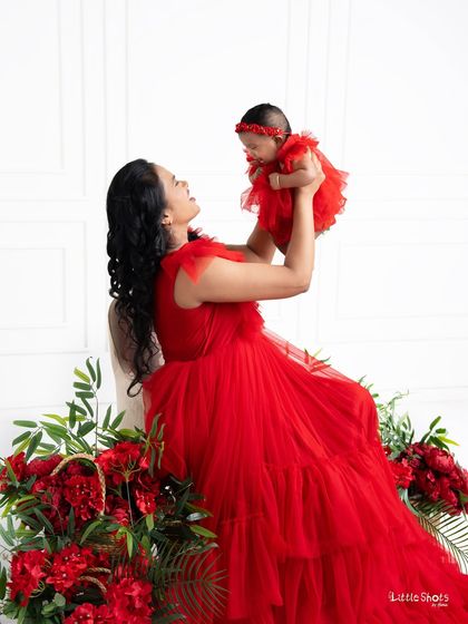 The pure joy of motherhood. This stunning shot of a mother lifting her baby, both dressed in vibrant red, creates a powerful and unforgettable image of their special bond.