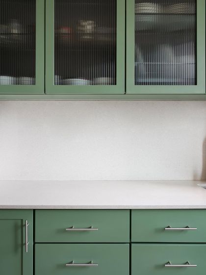 A close-up of the green kitchen cabinets I designed. The fluted glass adds a layer of texture and partially obscures the contents, maintaining a clean look while hinting at what's inside.