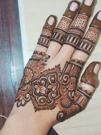 A close-up of the design I did for myself, featuring a central floral motif and detailed fingers.