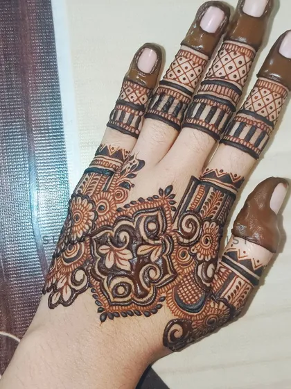 A close-up of the design I did for myself, featuring a central floral motif and detailed fingers.