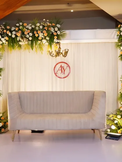 A simple yet elegant stage with a floral arch of peach and white roses. The clean white drapes and minimalist design make the couple the true focus of the celebration.
