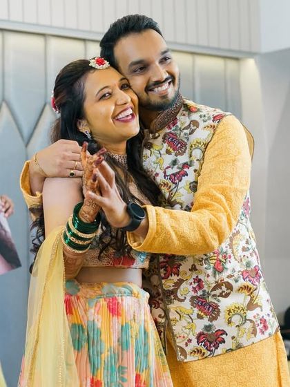 A couple embraces happily during their Sangeet celebration.