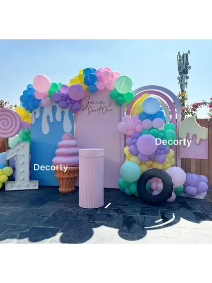 A vibrant and fun Candyland theme for a "Sweet One" first birthday. The outdoor setup features giant candy props and a colorful balloon arch.