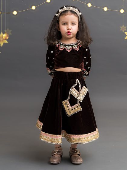 This chocolate brown velvet lehenga set comes with an adorable matching potli bag, perfect for little treasures.