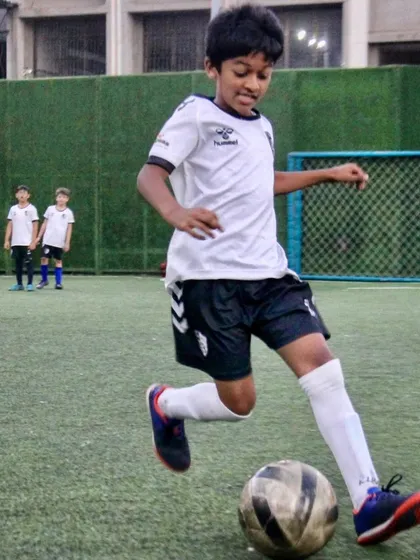A U10 player drives forward with the ball, displaying the confidence and dribbling technique we build from a young age.