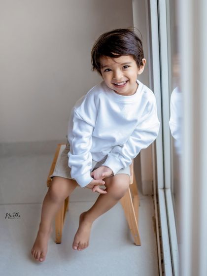 A happy little boy sitting by the window.