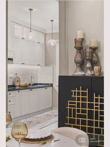 This view from the dining area looks towards the kitchen, revealing a harmonious design language. The black and gold cabinet in the foreground adds a touch of art deco glamour, connecting the two spaces.