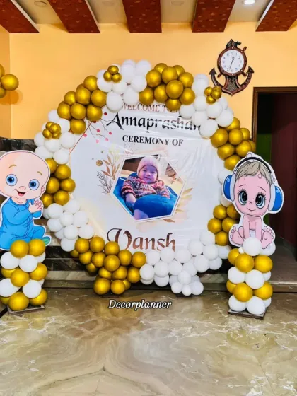 For a more modern take on the Annaprashan ceremony, I designed this beautiful setup with a gold and white balloon arch. The personalized backdrop featuring the baby's photo adds such a sweet, personal touch to this special milestone.