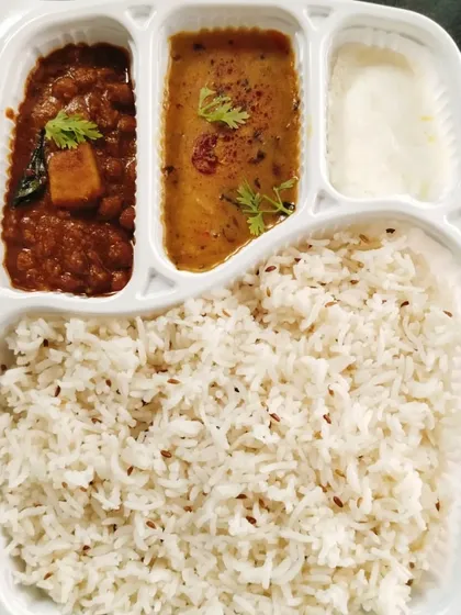 A combo meal of Jeera Rice, Dal Tadka, Aloo Chana curry, and curd. A simple, satisfying, and flavorful vegetarian option.
