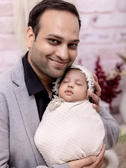 A proud father holds his sleeping newborn daughter. This portrait captures the gentle strength and love in a father's embrace, a memory to be treasured for a lifetime.