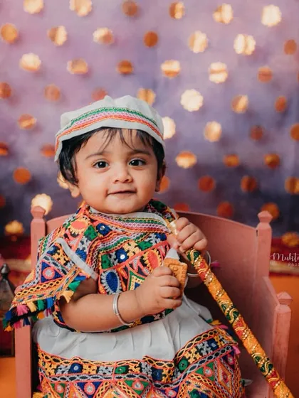 This little one looks so adorable in her traditional Gujarati outfit, complete with a cap and dandiya stick.
