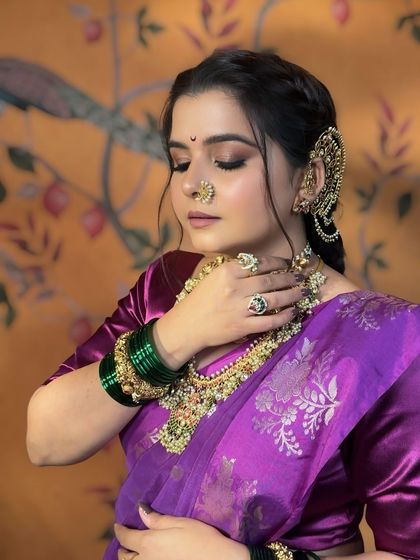 A close-up showcasing the detailed eye makeup and the traditional crescent bindi. The combination of smoky shadow and defined brows creates a captivating and timeless look.