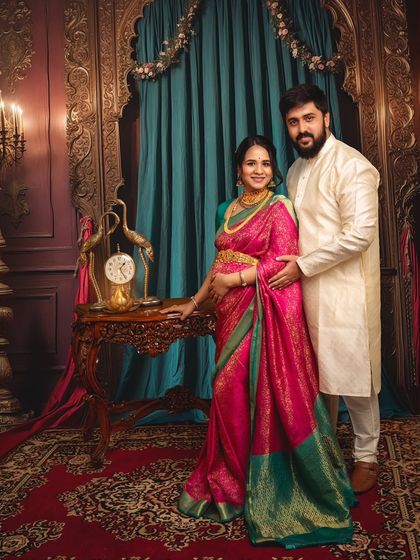 This full-length portrait showcases the couple in a grand, traditionally styled room. The intricate details of the decor and the elegance of their pose create a feeling of timeless heritage.