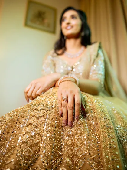 A detail-oriented shot focusing on the bride's intricate lehenga and engagement ring.