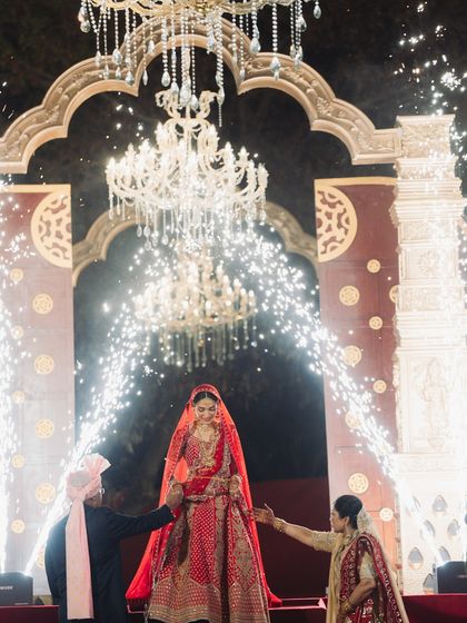 A touching moment as the bride is escorted by her parents. The grand archway and chandeliers provide a regal setting, while the cold pyros add a touch of celebratory sparkle to her walk.