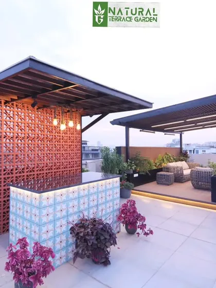A wide view of the Palam Vihar rooftop, showing the custom bar with its unique tile front and the separate pergola seating area.