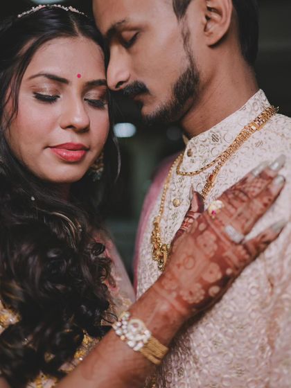 A close-up portrait focusing on the bride's hand on her groom, highlighting the henna and the emotional connection.