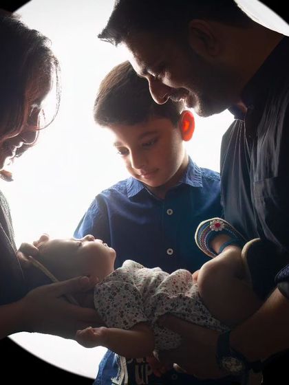 A beautiful backlit moment of a family welcoming their newborn twins. The silhouette style creates a sense of reverence and awe for this special time.