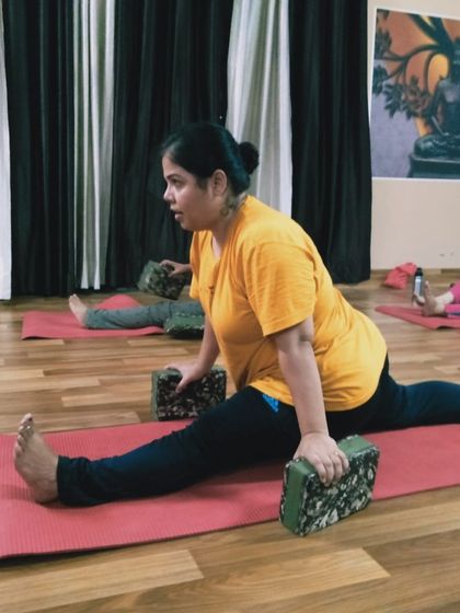 Another student practicing a supported split, showing that this pose is accessible to different body types with the right guidance and tools.