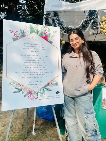 Posing proudly next to our menu at a Christmas market. The menu featured some of our bestsellers like Truffle Fries, Mexican Rice Bowls, and Hot Chocolate.