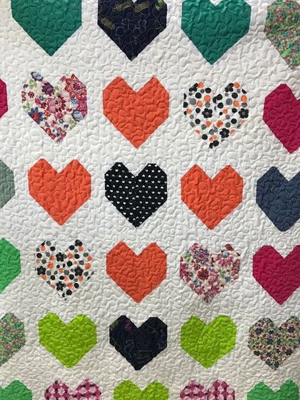 A lovely quilt featuring hearts made from a variety of colorful fabrics.