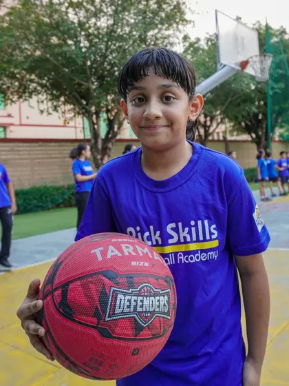 A young player holds his basketball with a proud smile. Passion is the driving force behind motivation and fulfillment, and we aim to nurture that passion in every child.