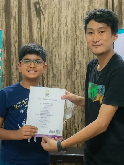 A young student smiles as he receives his Trinity College London music exam certificate.