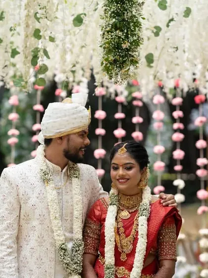 A happy, candid shot of the couple under a canopy of flowers, capturing the festive atmosphere of their wedding day.