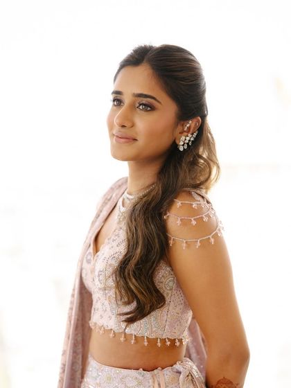 A close-up on the hairstyle and shoulder details of the blouse. The soft waves and ear cuff add a modern touch to the look.