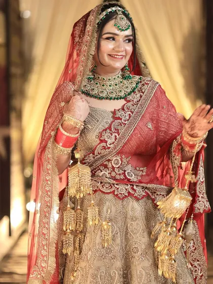 A happy bride ready for her wedding. Her look features a beautiful red dupatta, green emerald jewellery, and a radiant smile.