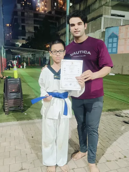 This student proudly displays his blue belt certificate. Each promotion is a significant milestone on the long but rewarding journey to black belt.