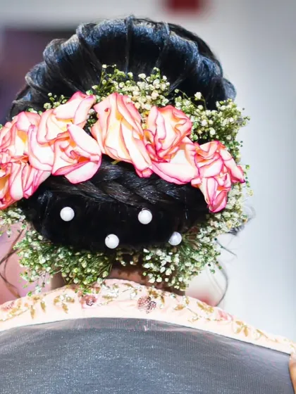 A close-up of a floral bridal bun, showing the detailed placement of roses and baby's breath.