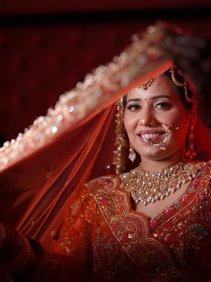A happy bride peeking through her dupatta. This shot captures a moment of pure joy and excitement.