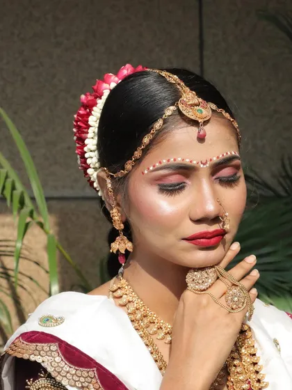 A close-up of the Konkani bride's makeup, focusing on the artistic 'bindi' work and the classic red lip.