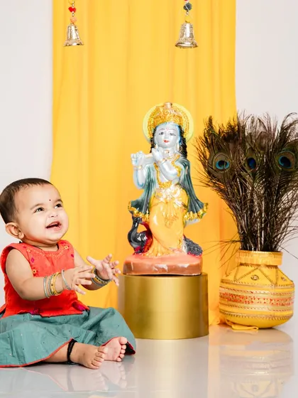 A candid moment of a baby girl looking up at a Krishna statue during our Janmashtami session. We create a reverent and joyful atmosphere for these special shoots.