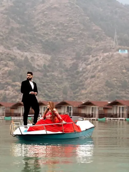 A stunning pre-wedding shot of the couple on a boat in Tehri, with the dramatic mountain landscape and floating huts creating a unique and memorable scene.