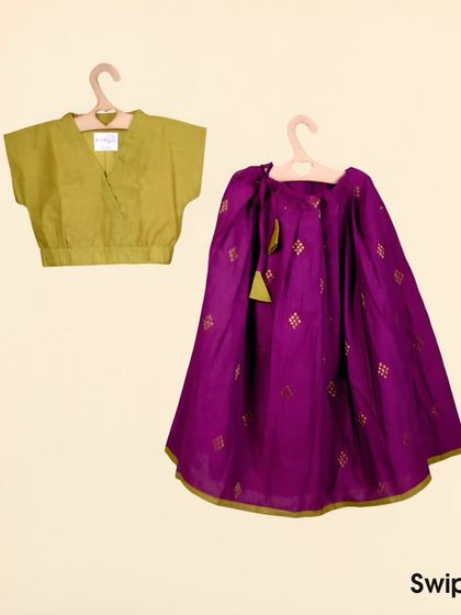 This ghagra choli set features a rich magenta skirt with gold buttis and a simple, elegant olive green crop top. It's a beautiful mix of traditional fabric and modern style.