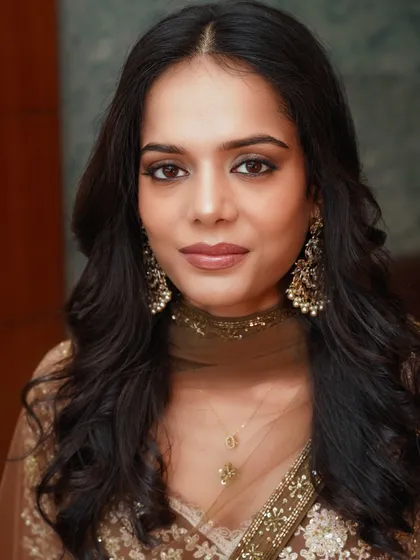 A stunning close-up portrait. The soft glam makeup features a bronze smokey eye and a nude lip, creating a look that is both sophisticated and modern.