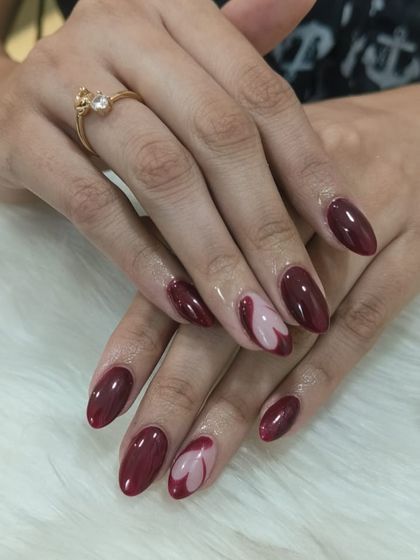 Another angle of the deep red nails with the negative space heart design. The almond shape of the nails adds to the overall elegance.