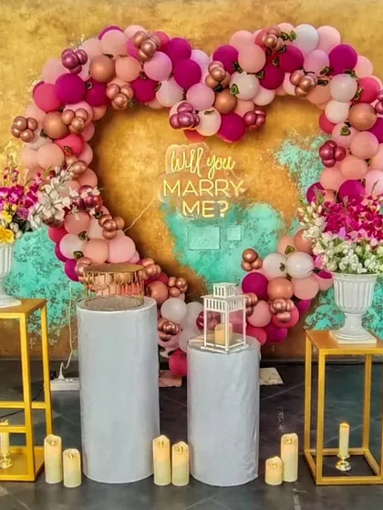 Make a bold statement with a custom balloon heart arch. This vibrant display in shades of pink and rose gold, complete with a "Will you Marry Me?" neon sign, creates a fun and festive backdrop for a memorable proposal.