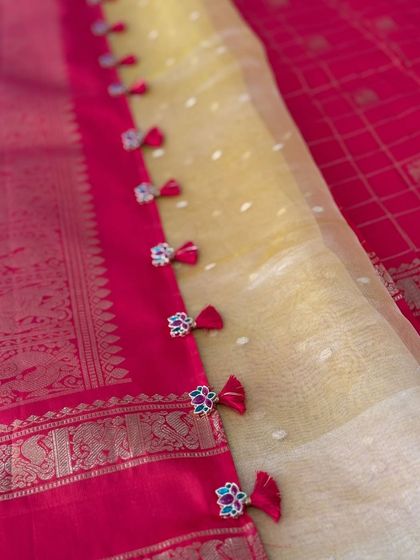 The border of a sheer yellow dupatta, adorned with our signature Jadau-style pendants and small red tassels for a playful yet elegant look.