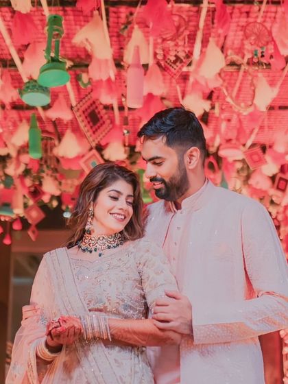 A tender moment between the couple at their Mehendi ceremony, set against a backdrop of intricate, personalized decor.