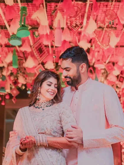 A tender moment between the couple at their Mehendi ceremony, set against a backdrop of intricate, personalized decor.