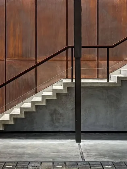 The beauty of a space is often found in the honest expression of its materials. In the Automobile Design Studio, a simple concrete staircase is set against a wall of weathered Corten steel, creating a powerful dialogue between raw texture and clean lines.