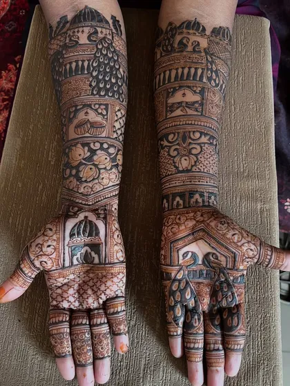 A close-up of a peacock-themed bridal mehendi. The design features multiple peacocks, palace windows (jharokhas), and other traditional elements.