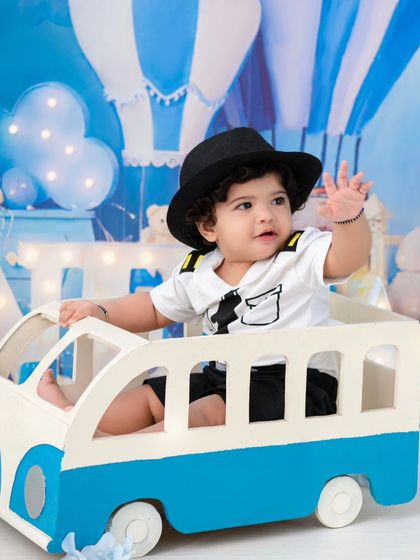 A happy passenger. The bus prop and hot air balloon background create a fun and imaginative travel-themed session.