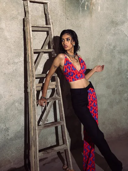 A high-fashion shot using a simple wooden ladder as a prop. The hard, directional light creates deep shadows and a gritty, industrial mood.