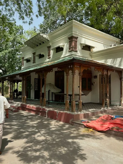 The restored verandah of a colonial bungalow, with its turned timber columns and traditional roof, providing a shaded space for relaxation.