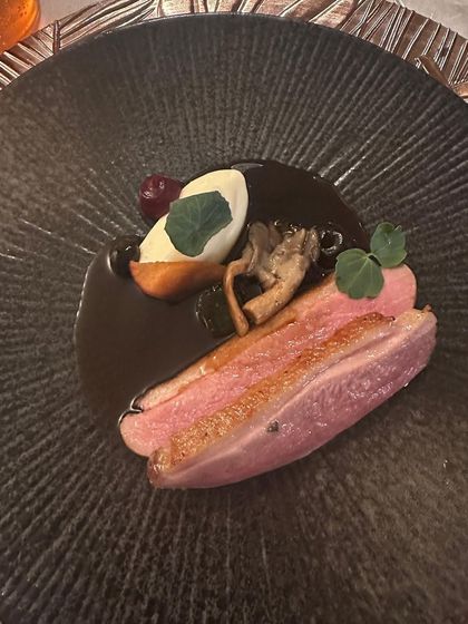 A stunning plate of Magret of Duck, cooked a la rosé. The dark, textured plate provides a beautiful contrast to the rich colors of the duck and sauce.