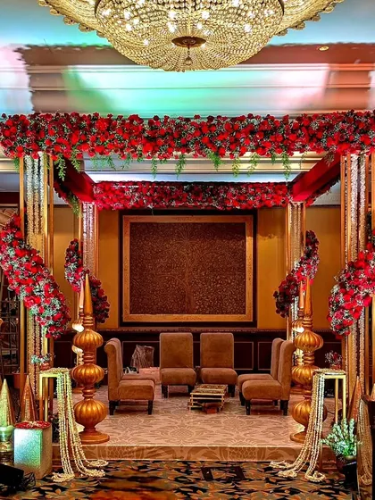 For this royal-themed wedding, I designed a grand mandap with ornate golden pillars, a canopy of red roses, and cascading floral strings, creating a truly regal setting.